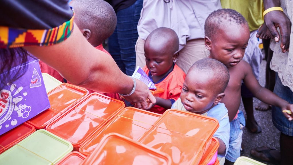 Young children receiving essential supplies from volunteers during a distribution event.